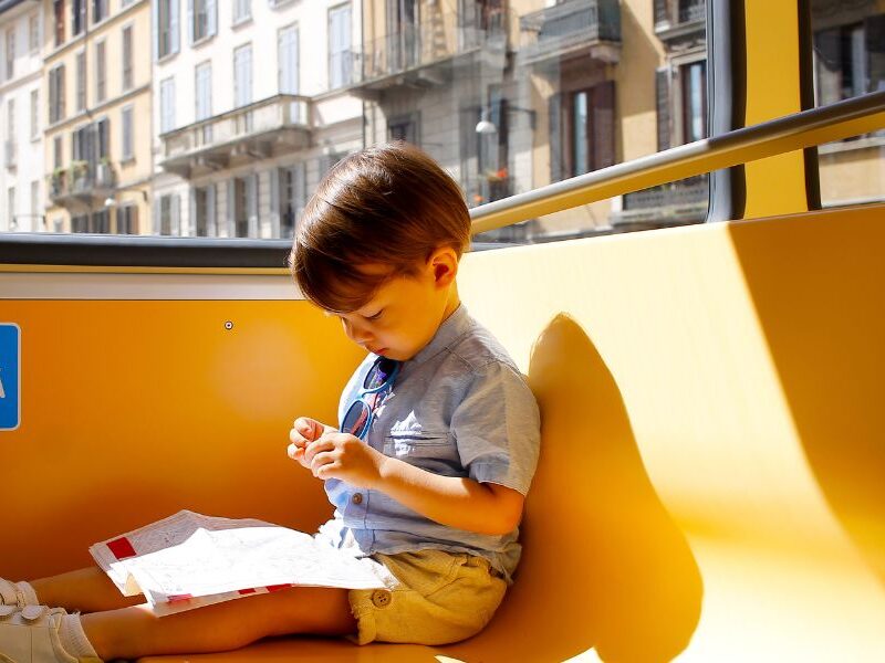 How to Pay for Kids on Public Transport in Paris: This is a picture of a little boy sitting on a train looking down at his hands.