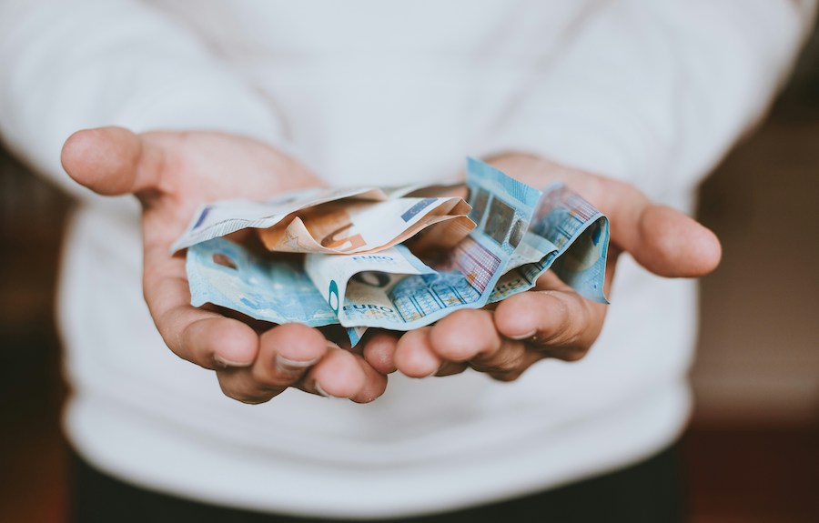 This is an image of a man extending his hands with a few European bank notes on them. An important thing to know before visiting Paris is that most places take card, but some will still require you to have small change.