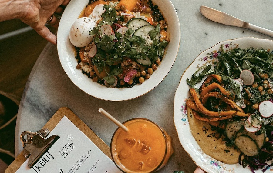This is an image of two beautiful vegetarian bowls that are packed with veges and meat-free protein. A glass of orange juice is also pictured.