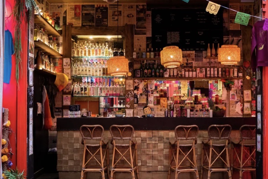 This is an image of a really cool Mexican bar with flags tied from the roof and wooden chairs and tables.