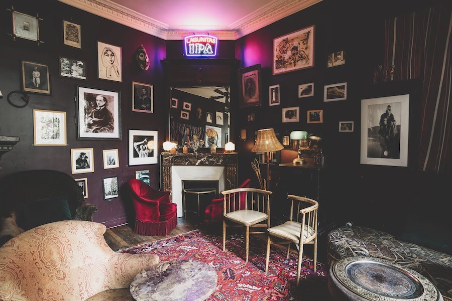 This is an image of a room with fun posters and art on the walls, plus comfy couches.