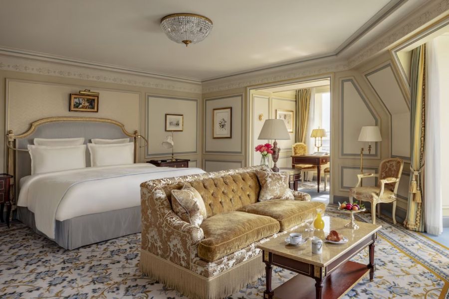 This is an image of a fancy hotel room in Paris with a bed, couch and coffee table.