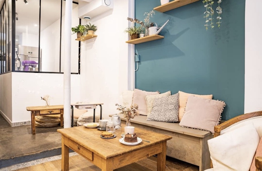This is an image of the interior of a café with couches and pillows to sit on, as well as a small coffee table to put food and drink.