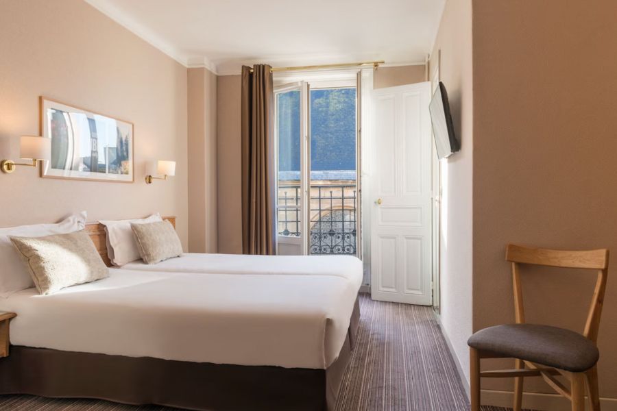This is a bright, airy hotel room with a small balcony. The decor is very minimalist and the linen is all white.