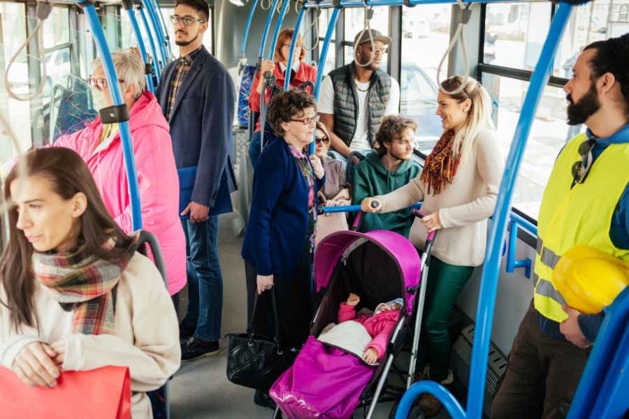 How to Pay for Kids on Public Transport in Paris: This is a picture of a woman with a pram, plus a bunch of other commuters just standing on a bus that is about to leave a stop.