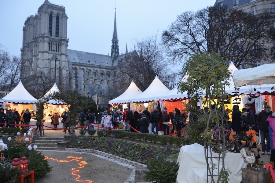 This is an image of a Christmas market with lots of little tents full of Christmas goods and the Notre Dame is at the back.