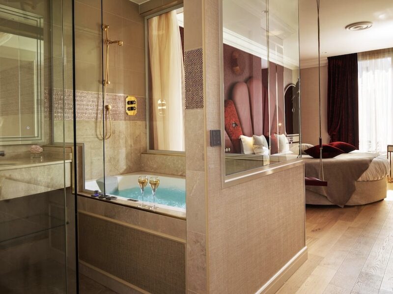 This is an image of a big hotel room with a large jacuzzi and double bed.
