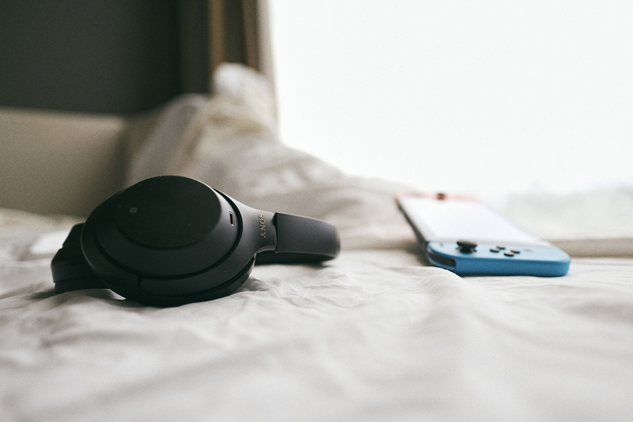 Noise-cancelling headphones resting on a bed, practical Paris travel accessories for flights, hotels and quieter travel.