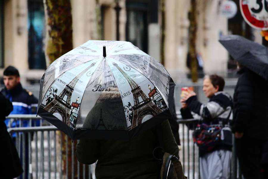 Traveller using an umbrella on a rainy day in Paris, one of the essential Paris travel accessories for unpredictable weather.