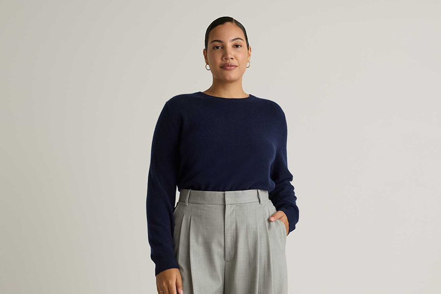 Woman wearing a navy sweater with grey tailored trousers, a simple outfit for how to blend in with Parisians.