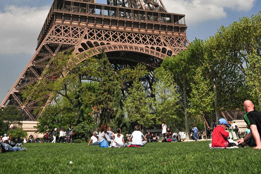 Families enjoying a picnic near the Eiffel Tower, one of the easy places to eat with kids in Paris.