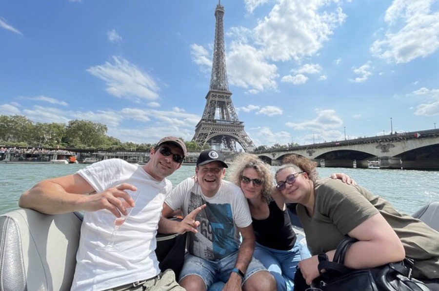 This is an image of people in a small cruise boat around the Seine. The Eiffel Tower is in the background.