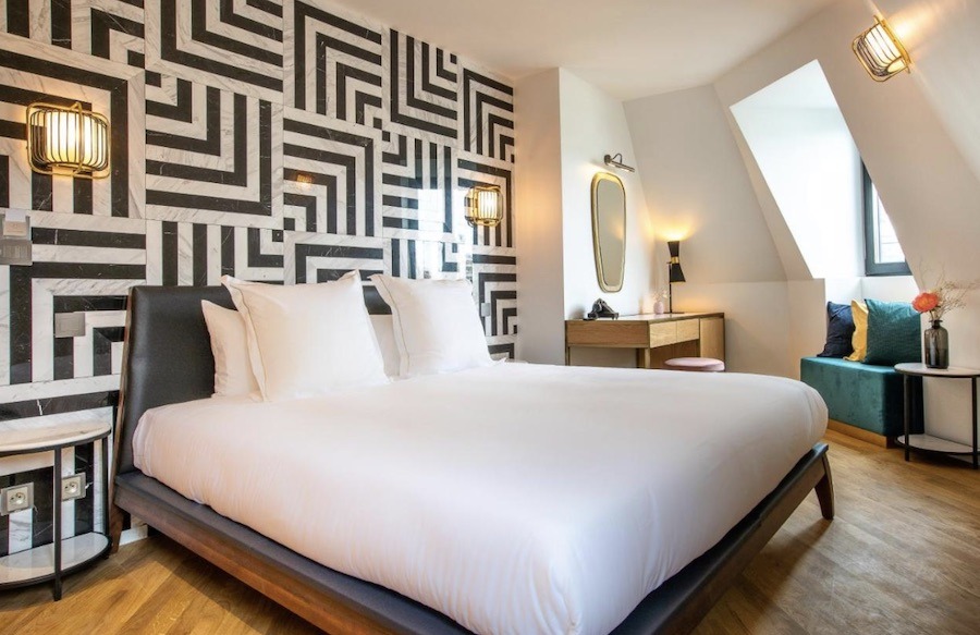 This is an image of a pretty minimalist hotel room. The only exception to the minimalism is the brown and white patterned feature wall.