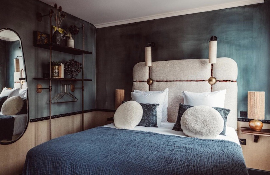 This is an image of a hotel room with blue walls and a bed with blue bedding.
