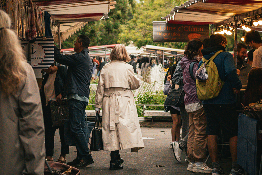 Shoppers browsing a lively Paris food market, a great place to pick up supplies for Thanksgiving in Paris.