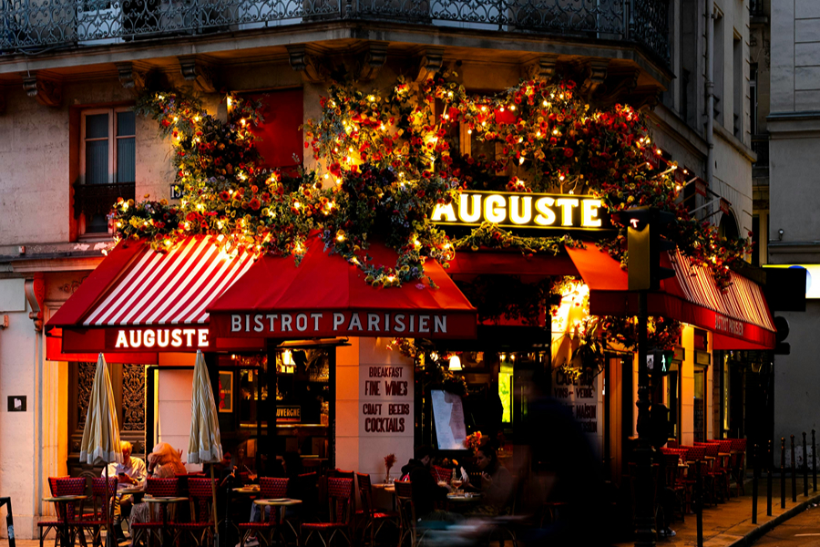 Parisian bistro glowing with warm lights in the evening, a cosy place to enjoy Thanksgiving in Paris.