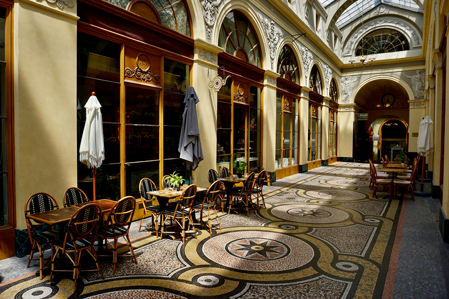 Historic covered passageway in Paris with café tables and ornate architecture, a cosy place to explore around Thanksgiving in Paris.