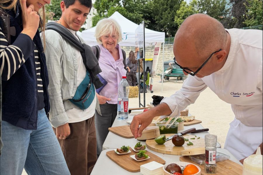 A chef named Charles Sousa plates bite-sized appetizers for onlookers at an outdoor food demonstration during Paris's Taste Week.