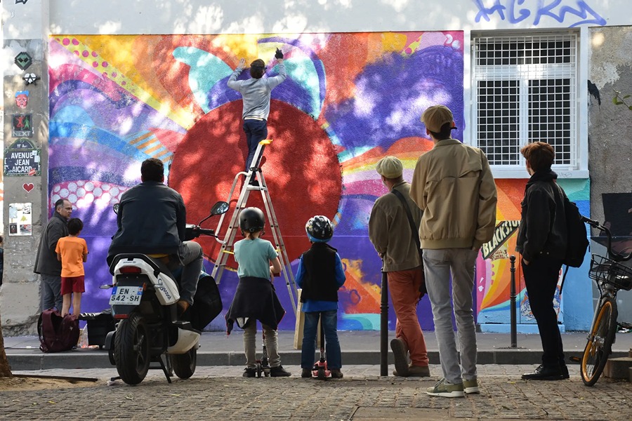 An artist painting a colourful mural on a street art tour in Belleville, one of the best things to do in September in Paris.