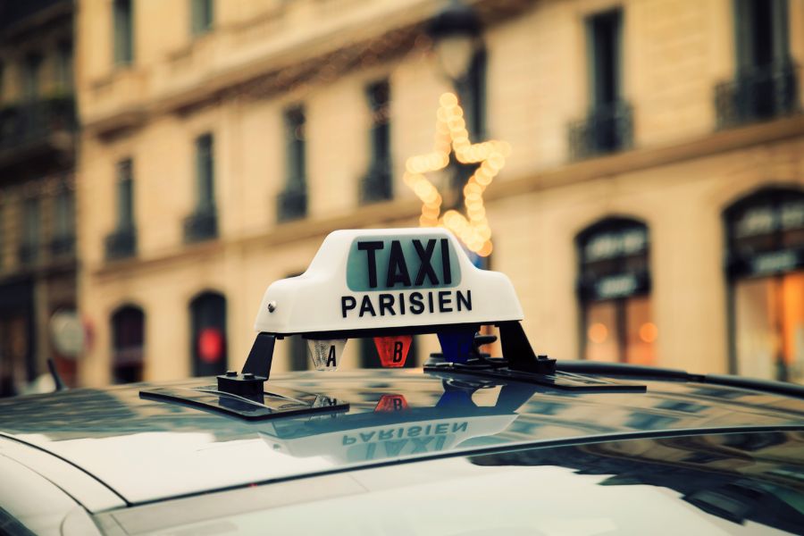 This is an image of a taxi driving in Paris. Only the hood of the car can be seen.