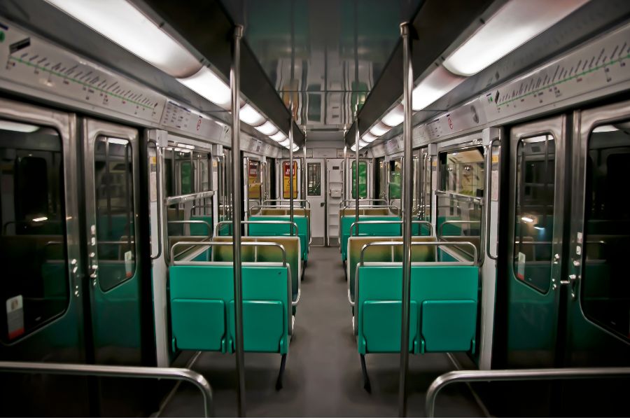 This is an image of the inside of a Paris metro train. There are no people in sight. The seats nearest to the doors are folded up to make more room.