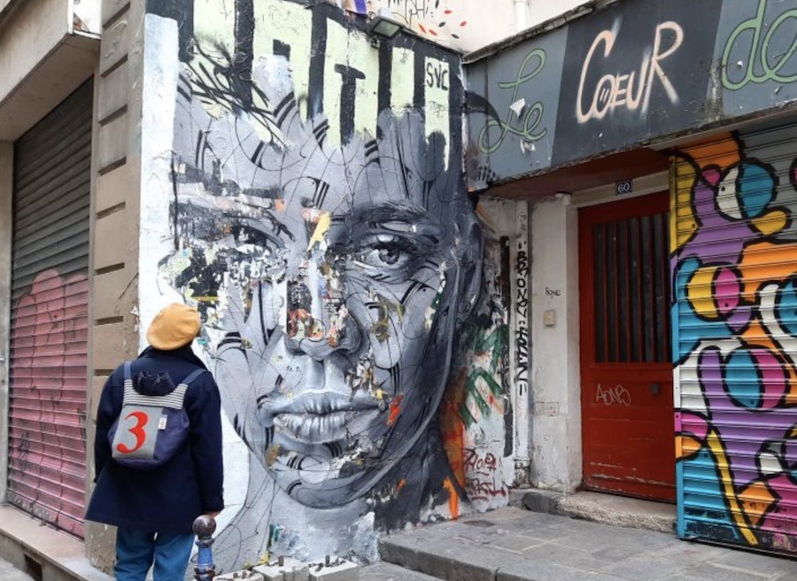 This is an image of a person gazing up at beautiful street art of a woman's face.