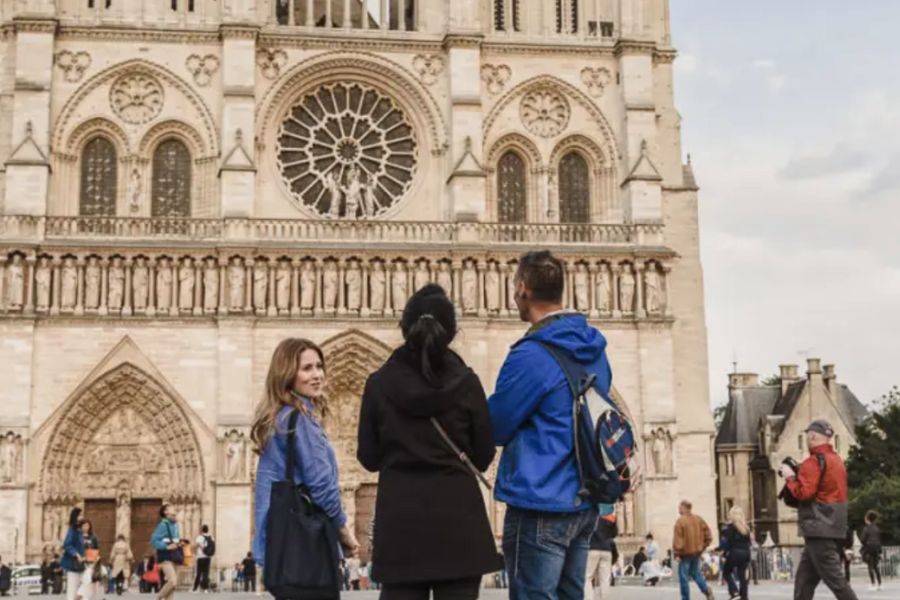 This is an image of a group of people staring up at the Notre-Dame with a tour guide.