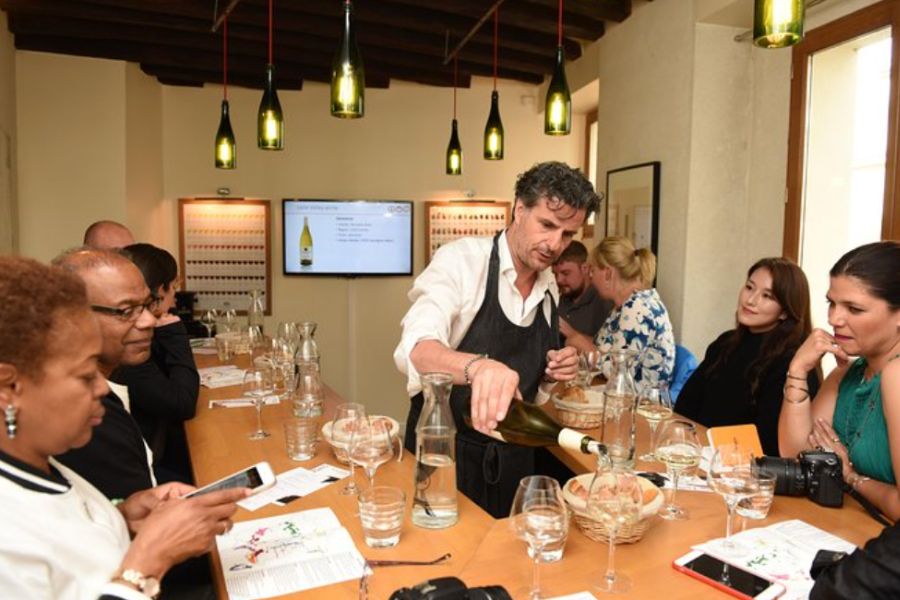 This is an image of a man pouring wines with a tour group surrounding him tasting it.
