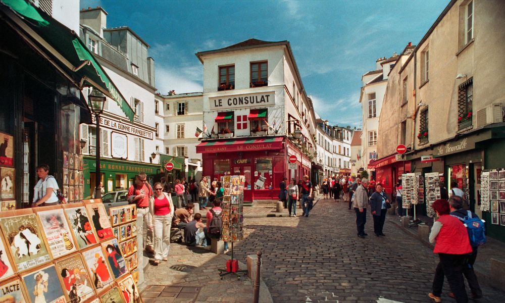 This is an image of the cobblestone streets in Montmartre with people walking down.
