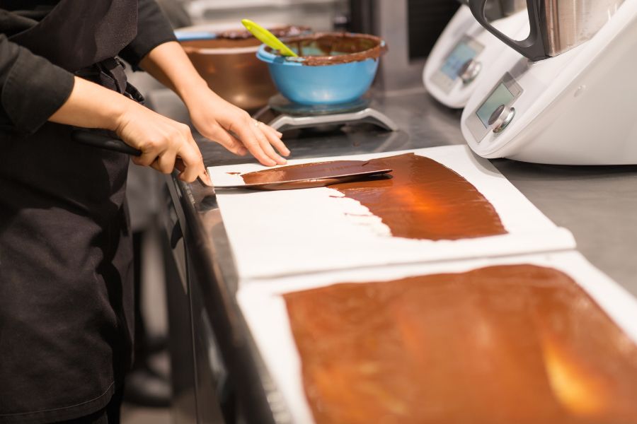 This is an image of a person spreading chocolate on a mould.