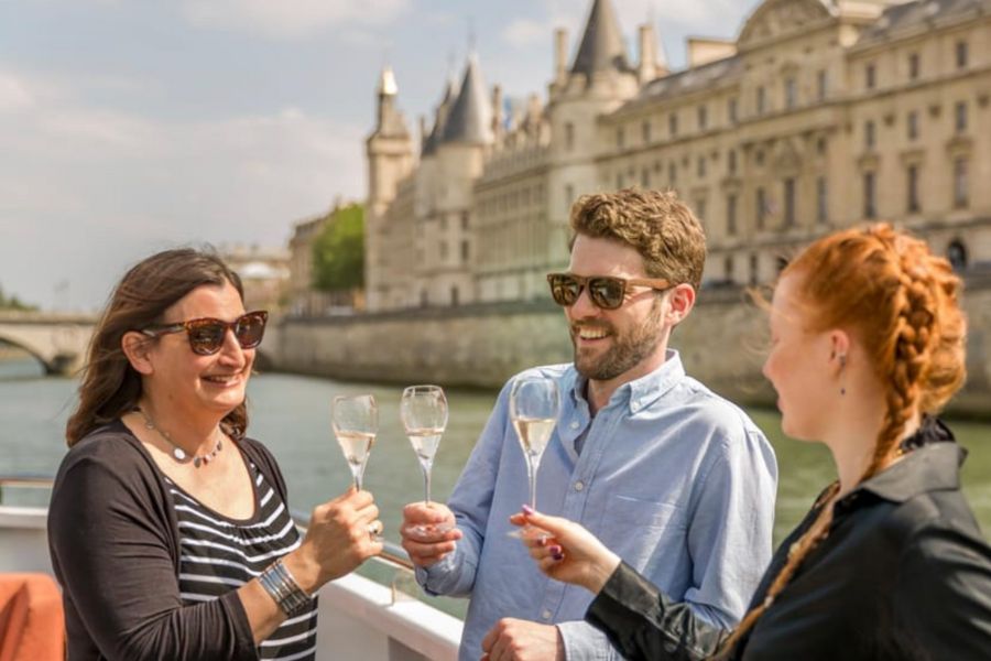 This is an image of three people clinking champagne glasses while on a boat on the Seine River.