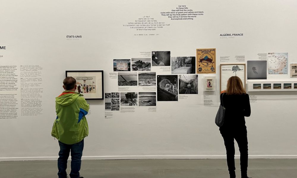 This is an image of two people staring at a big white wall full of posters and writing on it.