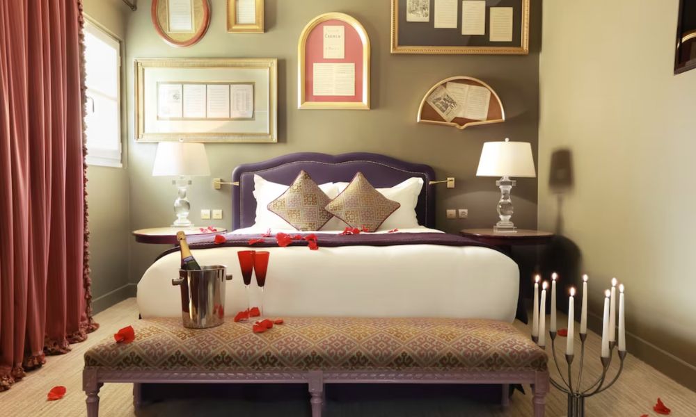 This is an image of a romantic hotel room with a double bed full of rose petals and champagne.