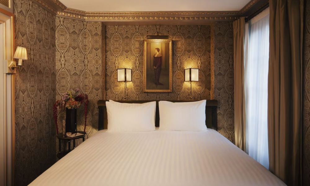This is an image of a dark-lit room with funky wallpaper and a double bed.
