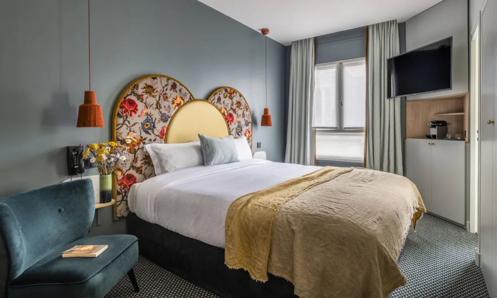 This is an image of a hotel room with nice decor and flowers and a double bed.