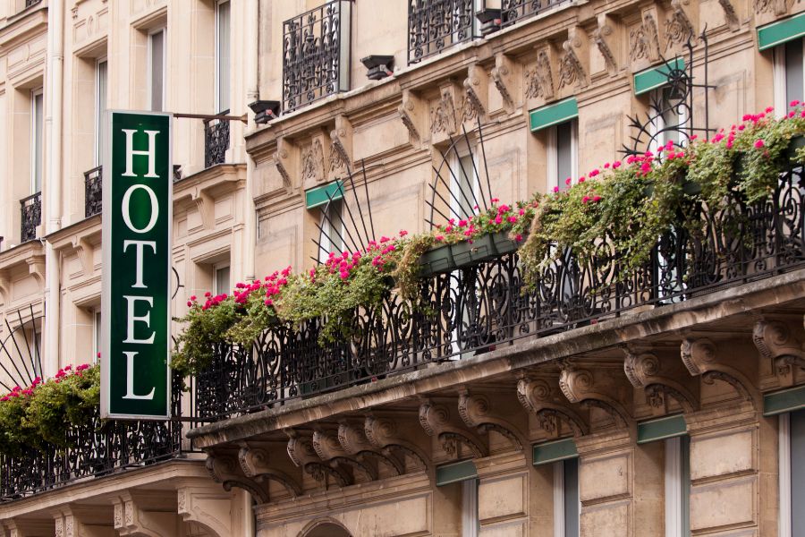 This is an image of the exterior building of a Paris hotel with balconies full of flower pots and more.