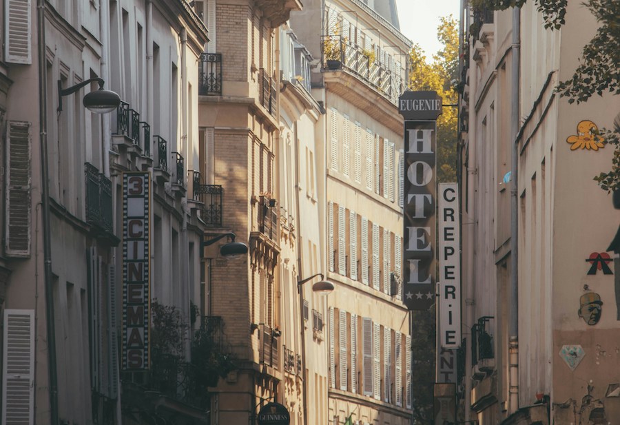 This is a very Parisian street with rows of apartments fitted with black balconies. There is a sign on one side saying "Hotel".